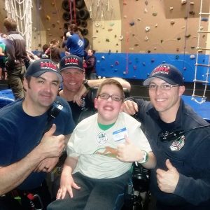 JoJo poses with the firefighters who helped him reach the top of a 30-foot climbing wall.